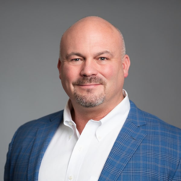 Mike Dulin, Chief Executive Officer of Circulus, is a bald man with a short beard and mustache, wearing a white shirt and blue plaid jacket. He smiles at the camera against a neutral background.