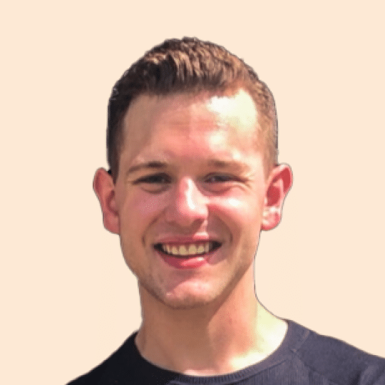 A man with short, dark hair and fair skin is smiling at the camera. This is Alex Pastor, wearing a black shirt against a plain background.