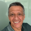 A man with short gray hair and a gray shirt, identified as Alvaro Cuba, smiles at the camera.