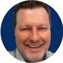 A close-up photo of a smiling man with short dark hair, a light complexion, and a trimmed beard, set against a blue background, embodies the spirit of improving reliability in your plant.